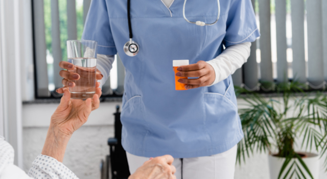 Cropped view of african american nurse holding pills and glass of water near senior patient